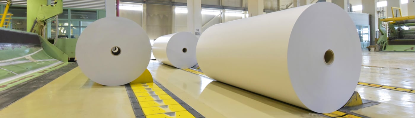 Large rolls of paper being processed in a paper mill